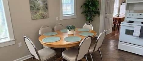 A dining area with a round table, chairs, and a potted plant.