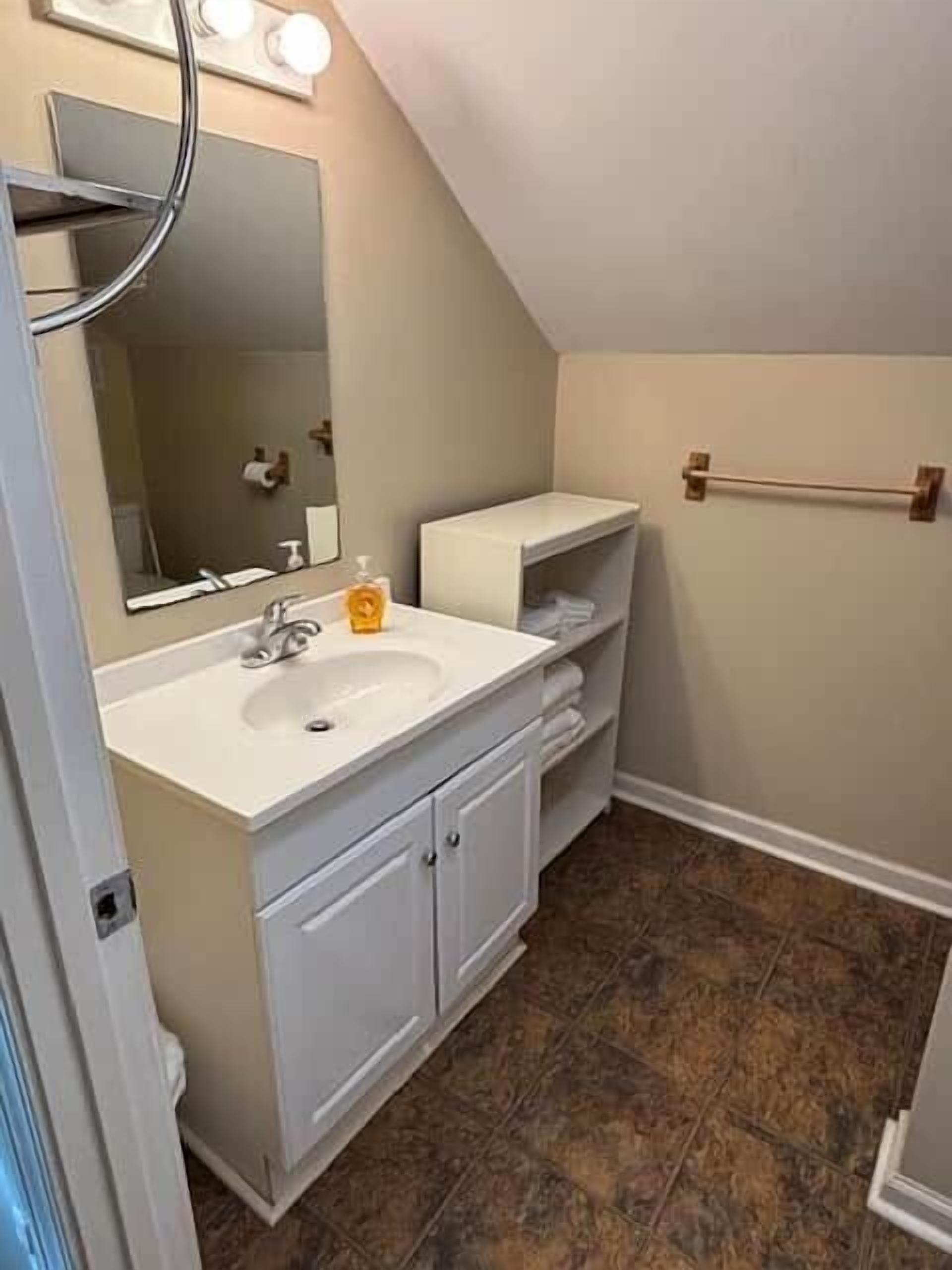A bathroom with a white vanity, a mirror, a towel rack, and a toilet.