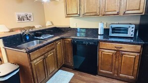 A compact kitchen with wooden cabinets, a dishwasher, a microwave, and a sink.