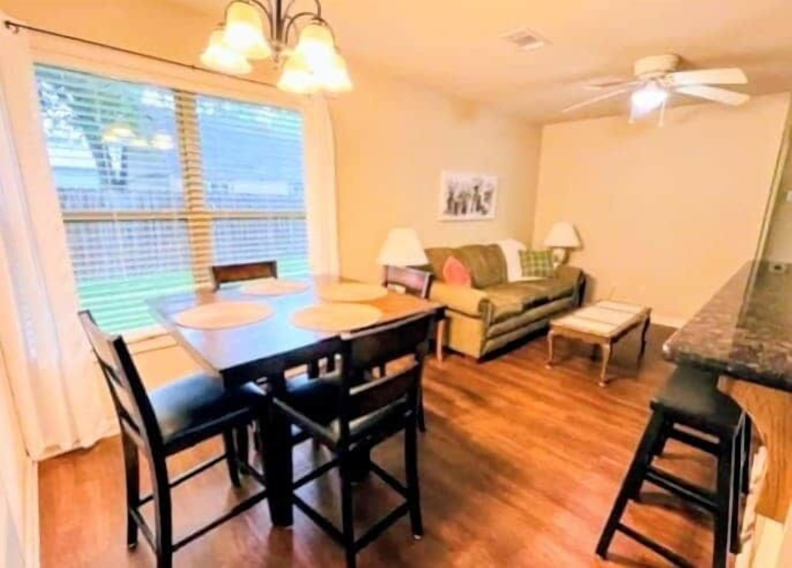 A dining area with a table and chairs, a sofa, a small table, and a ceiling fan.