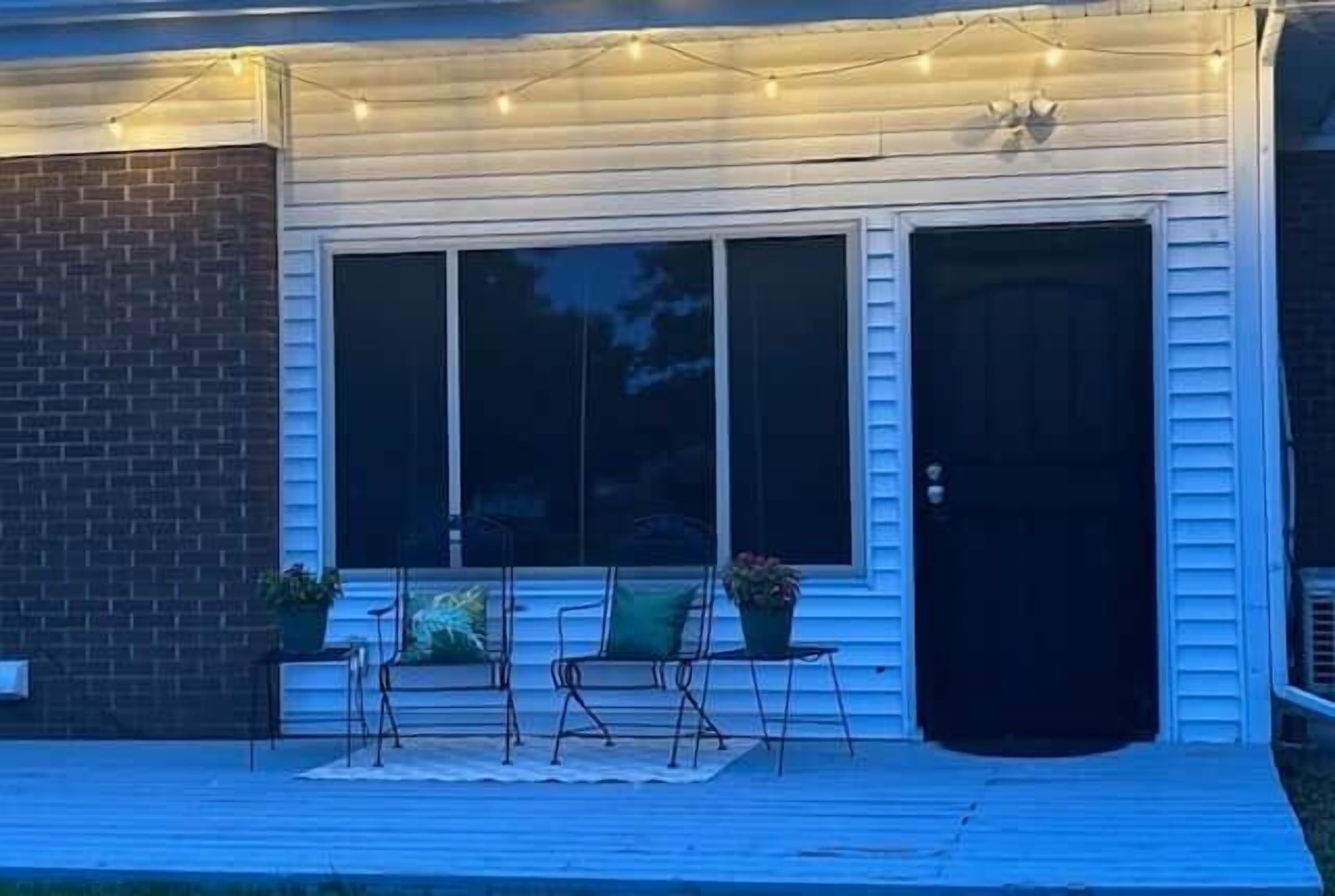 A porch with outdoor seating, a brick wall, and a door.