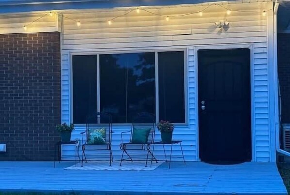 A porch with outdoor seating, a brick wall, and a door.
