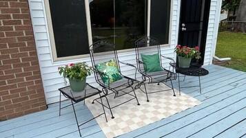 A porch with two chairs and potted plants.