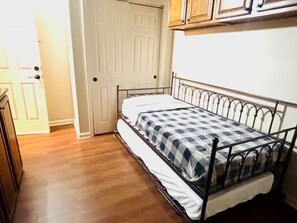 A small room with a single bed, a door, and wooden cabinets.