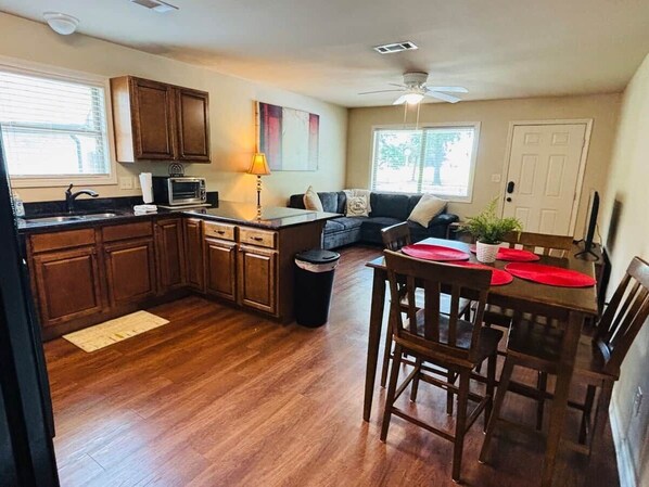 A kitchen with wooden cabinets, a microwave, and a dining area with a table and chairs.