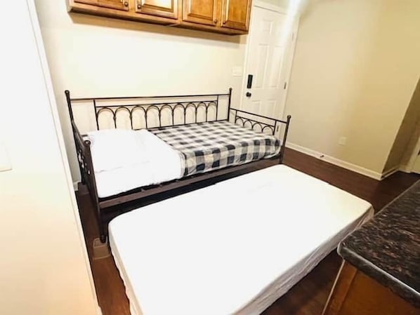 A small room with a bed, a wooden cabinet, and a white door.
