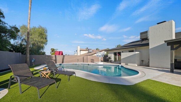 A backyard with a swimming pool, artificial grass, and lounge chairs. - Desert Retreat with Pool & Mountain Views (Phoenix)