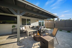 A covered patio area with a fire pit, outdoor furniture, and a view of the surrounding landscape. - Desert Retreat with Pool & Mountain Views (Phoenix)