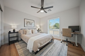 A bedroom with a bed, bedside tables, a desk with a chair, a ceiling fan, a window with blinds, and a framed artwork on the wall. - Desert Retreat with Pool & Mountain Views (Phoenix)