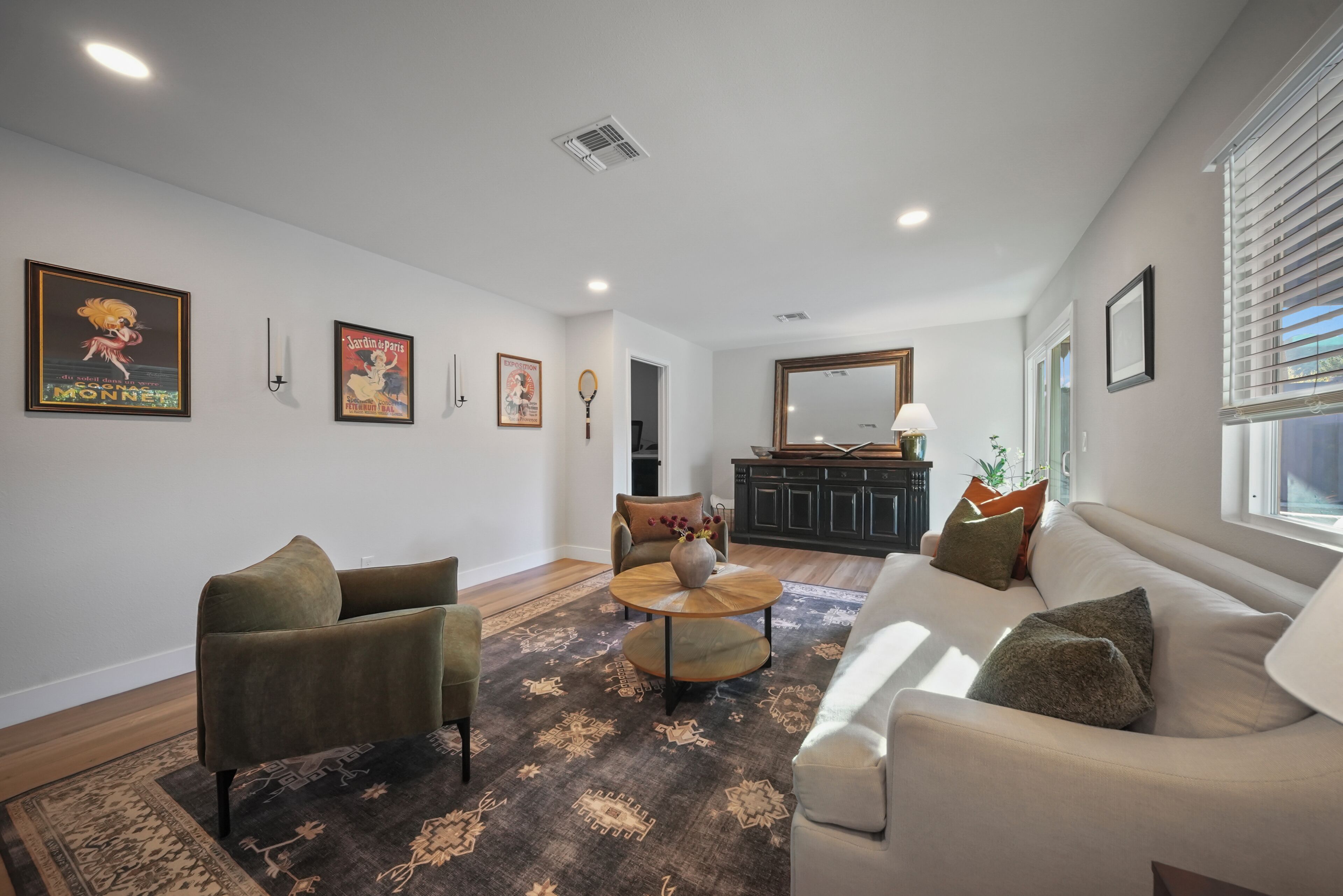 A living room with a sofa, armchairs, a coffee table, and a patterned rug.