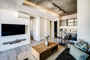 En moderne stue med et fladskærms-tv, et træsofabord, en sofa og et spiseområde med stole og et bord.