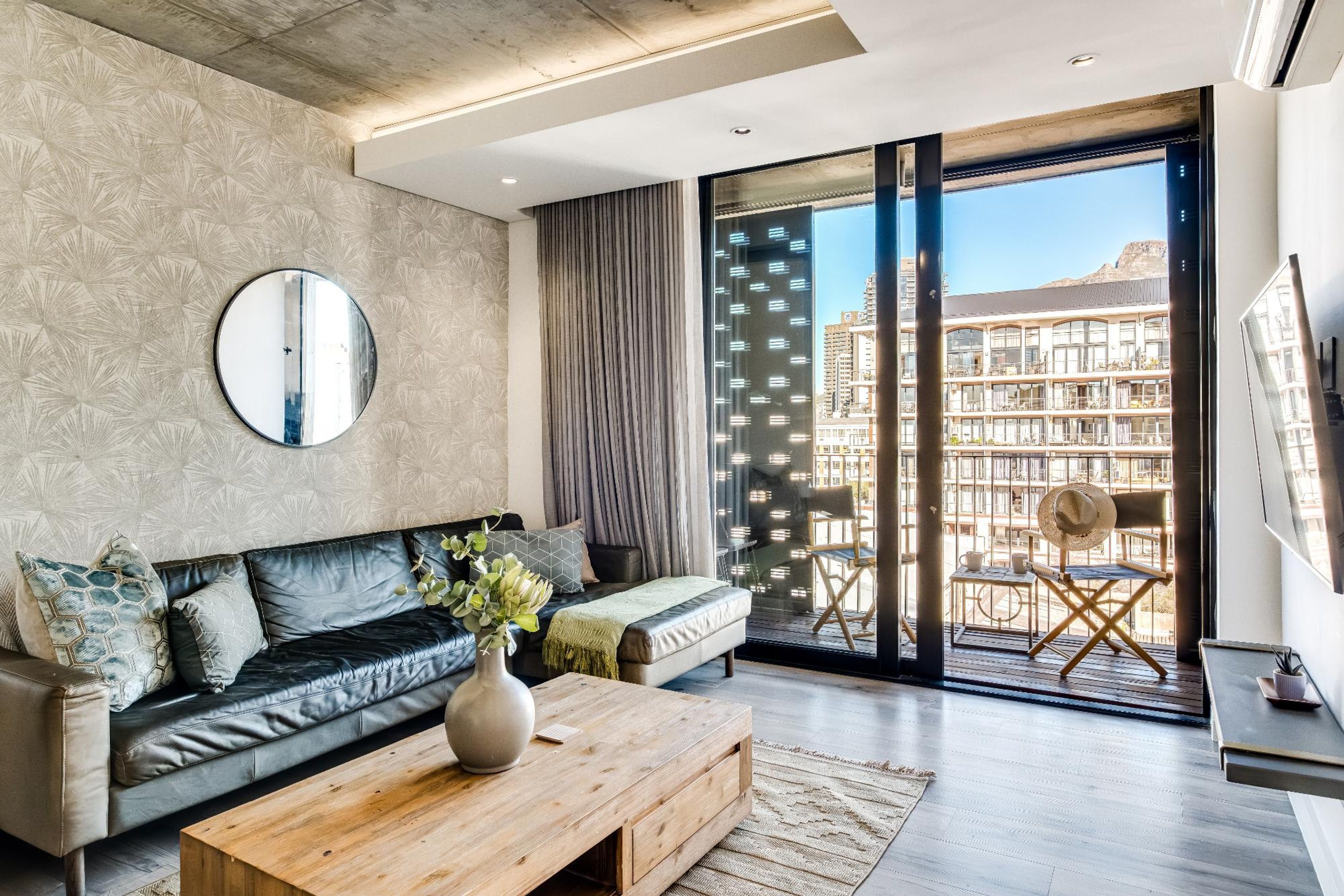 A modern living room with a leather sofa, a wooden coffee table, and a large mirror.