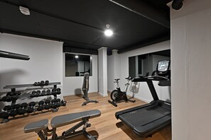 Un gimnàs a casa amb cinta de córrer, bicicleta estàtica, banca per a presses i peses.