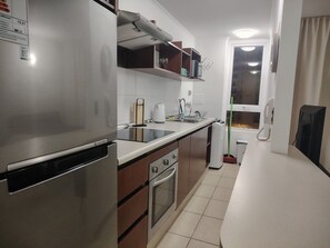 Eine kleine Küche mit Kühlschrank, Backofen und Spüle.
