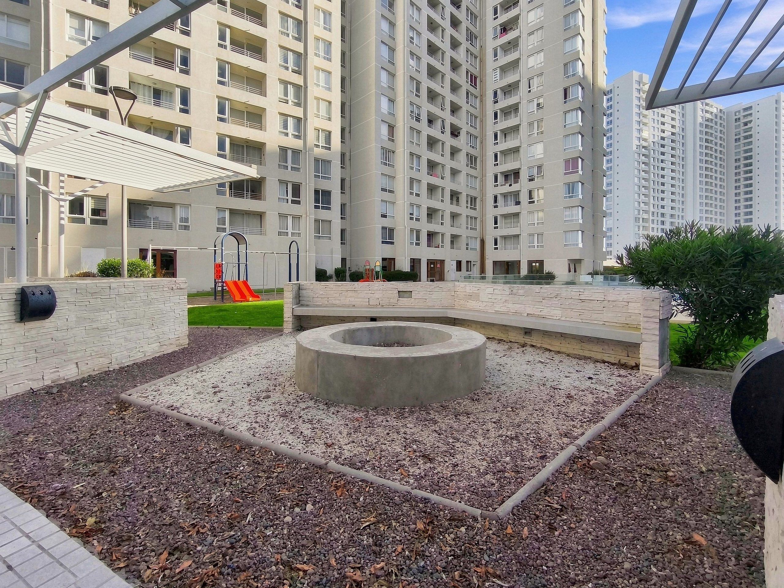A courtyard with a fire pit, a children's play area, and a modern building with balconies.