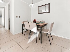 A dining area with a table set for two, chairs, a hanging light fixture, and a wall-mounted mirror. - Oceana Suites La Serena Peñuelas (Coquimbo)