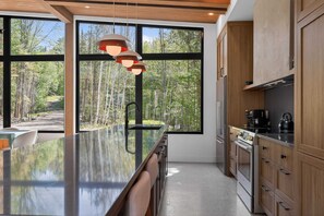 A modern kitchen with large windows, a central island, and wooden cabinetry.