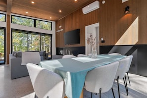 Um interior moderno com área de jantar, um sofá e uma TV.