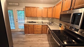 A kitchen with wooden cabinets, a stainless steel microwave, and a black stove.