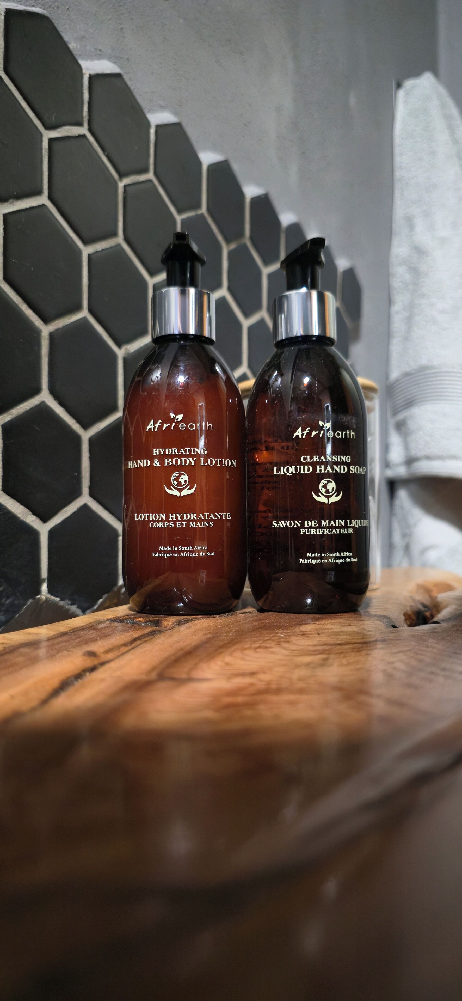 Two bottles of Afriearth hand and body lotion and liquid hand soap on a wooden surface.