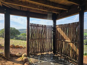 Un espace extérieur abrité, doté d’un élément aquatique, de poutres en bois et offrant une vue sur le paysage.