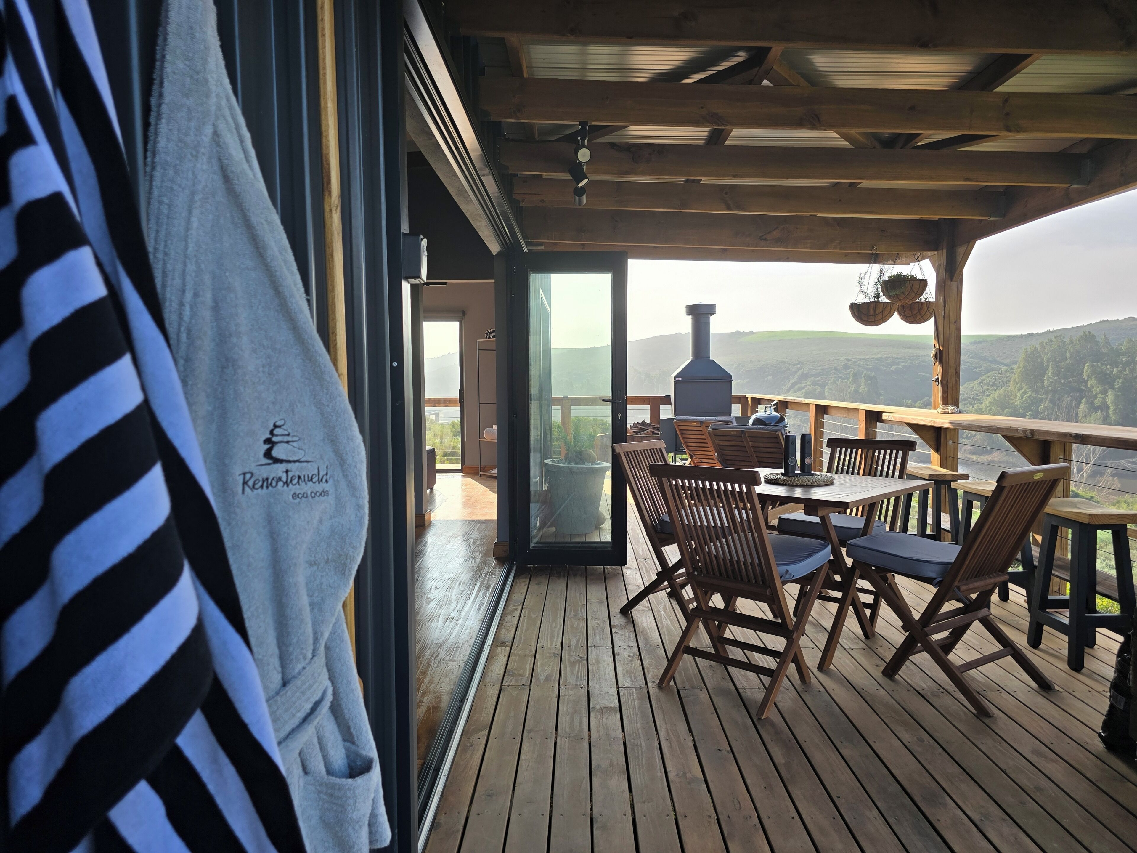 Une terrasse en bois avec des sièges extérieurs et une vue sur le paysage.