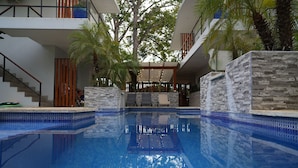 An indoor swimming pool with clear blue water, surrounded by stone walls and palm trees.