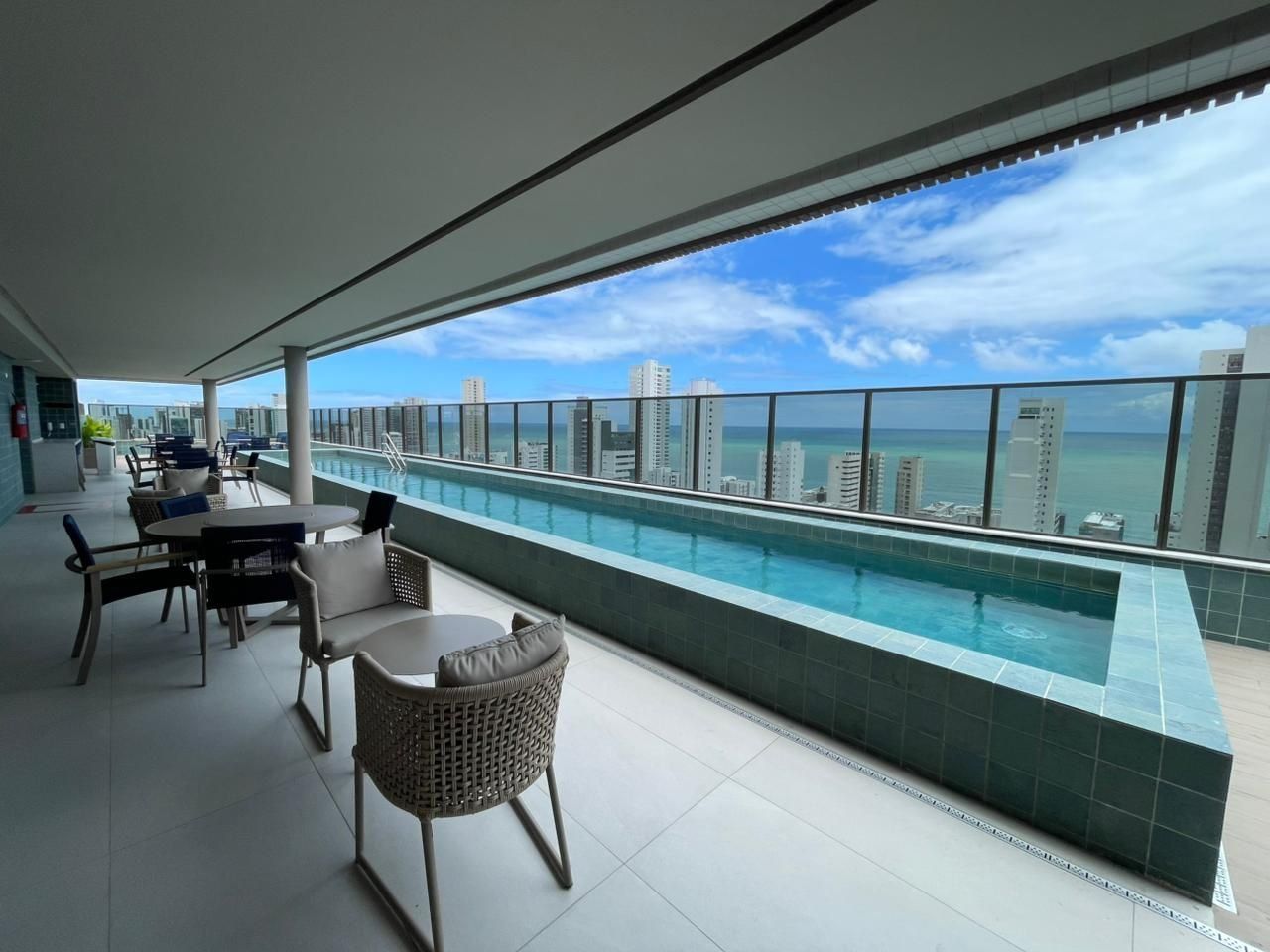 A rooftop terrace with a pool, seating area, and a view of the city skyline.