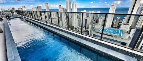 Una piscina en la azotea con vistas a la ciudad, rodeada de edificios altos.