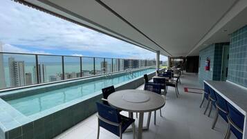 Un bar en la azotea con piscina, asientos y vistas del horizonte de la ciudad.