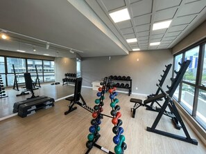 Une salle de sport équipée de matériel de musculation, d’haltères et de bancs.