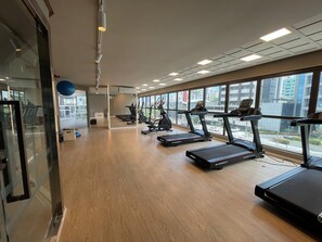 A gym with treadmills, exercise bikes, and a mirrored wall. - Icon Design Living por YOLO (Recife)