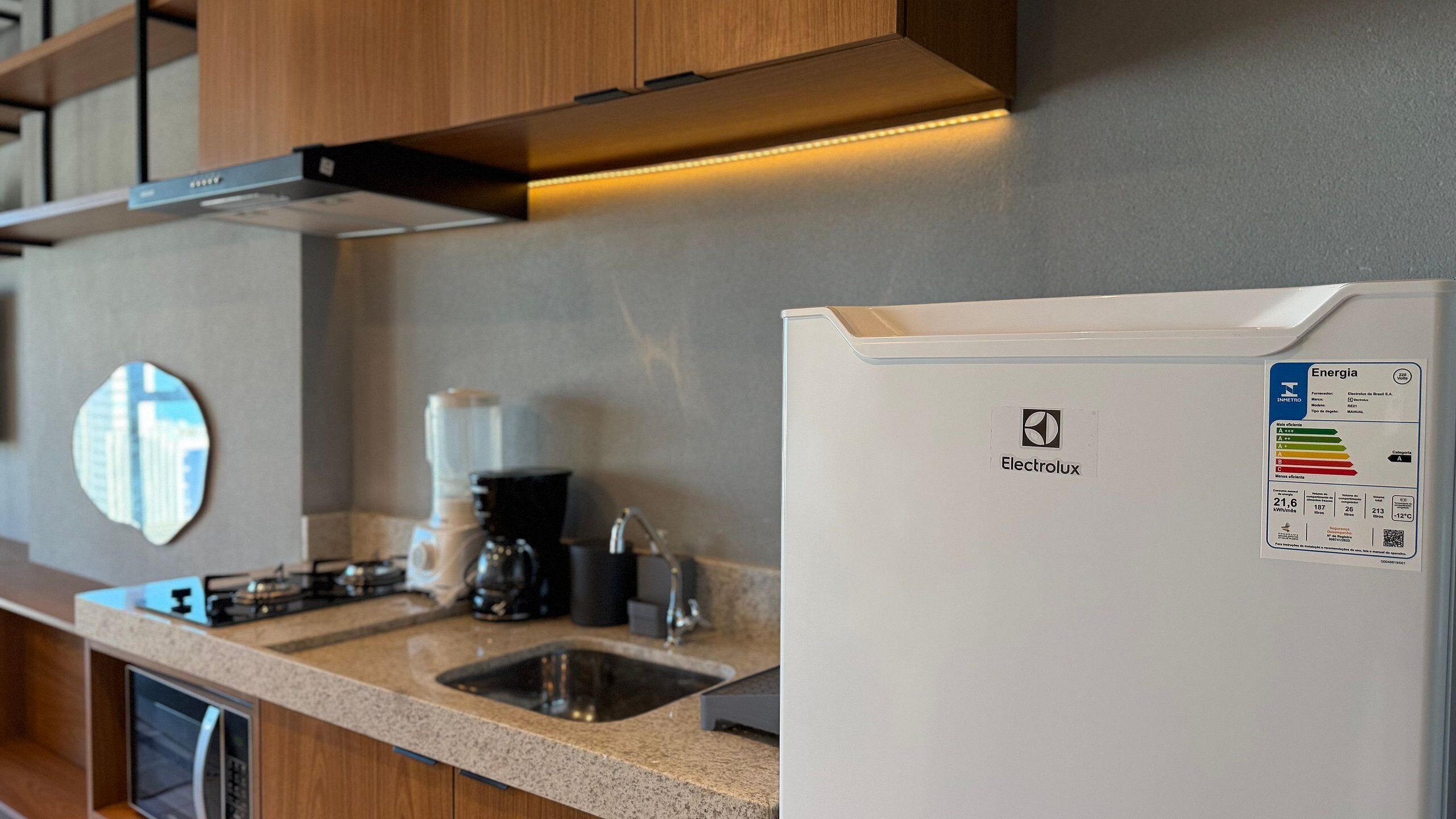 Una cocina con un refrigerador blanco Electrolux, una cafetera y un lavamanos.