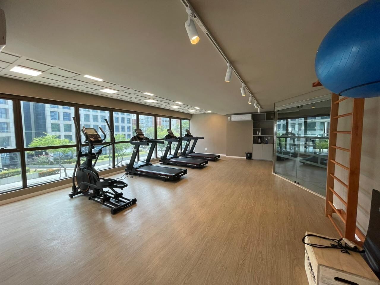 Un gimnasio con equipo de ejercicio, ventanas amplias y vistas al exterior.