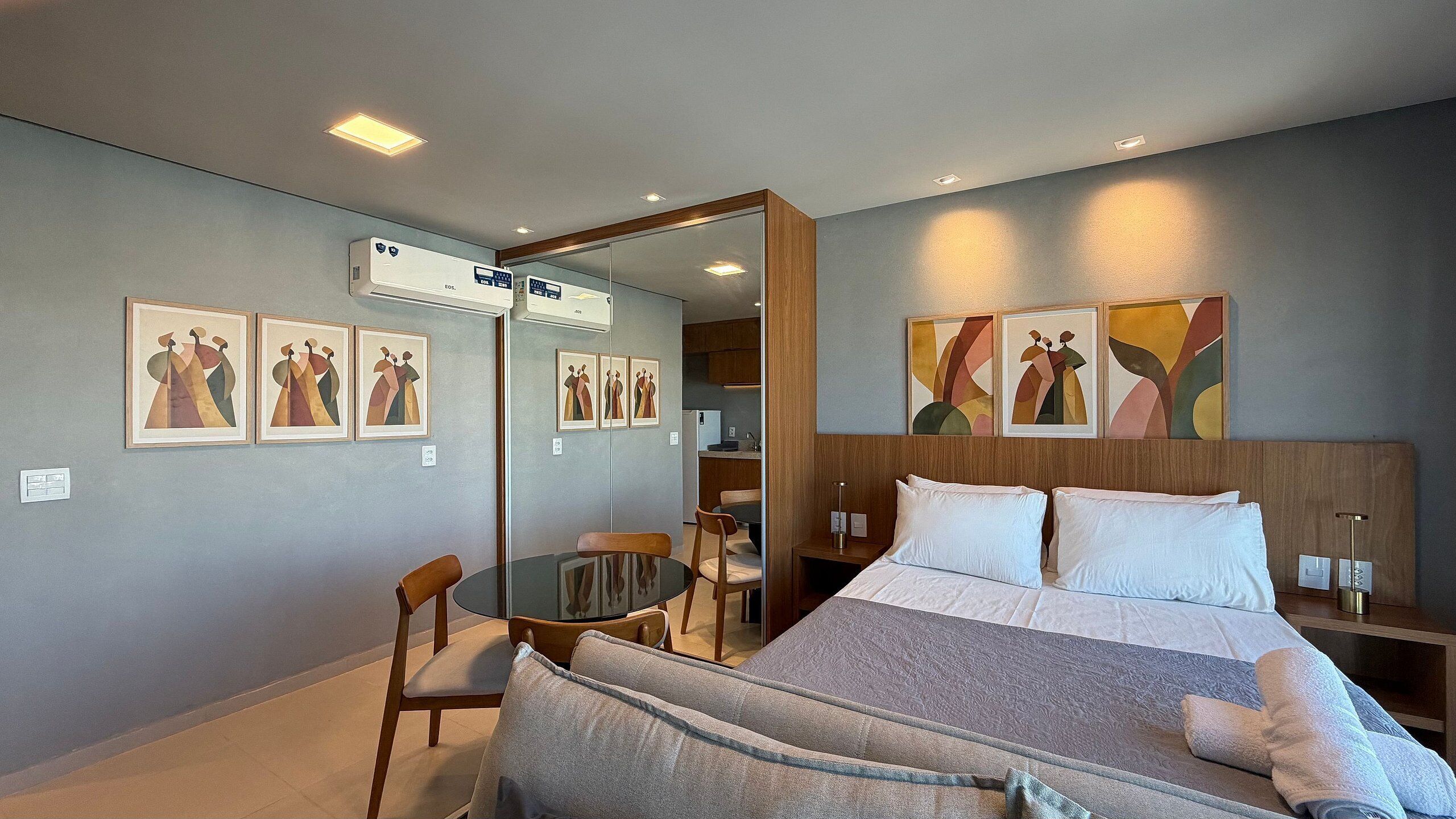 Una habitación de hotel con una cama, un escritorio, sillas y obras de arte en las paredes.