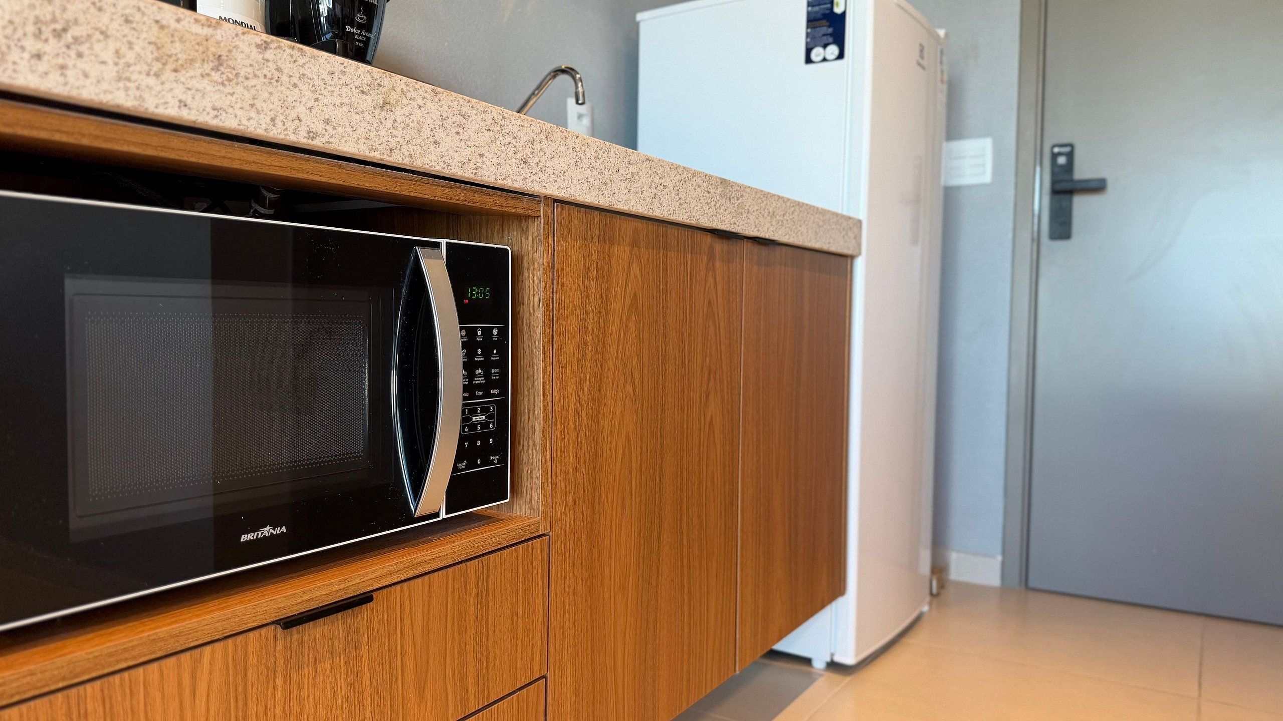 Una cocina con microondas, armarios de madera y un refrigerador blanco.