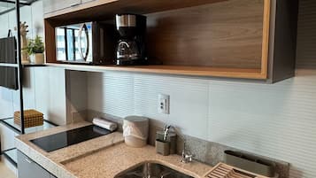 Una cocina moderna con encimera de granito, pileta de acero inoxidable y estantes de madera.