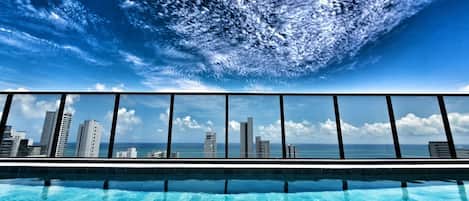 Piscina com vista para o horizonte urbano através de um guarda-corpo de vidro.