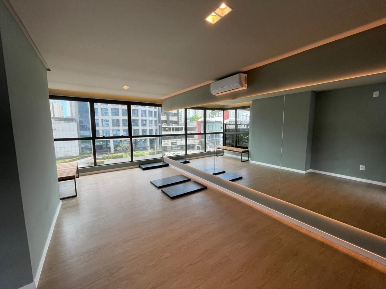 Una habitación amplia con un banco largo, una mesa pequeña y un banco junto a la ventana.