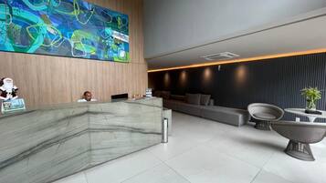 Un espace d’accueil moderne, doté d’un comptoir de réception en marbre, d’un grand tableau abstrait et de mobilier contemporain.