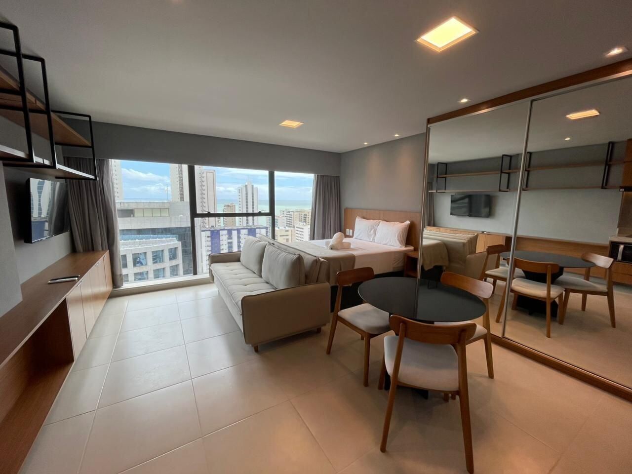 Una habitación de hotel moderna con cama, sofá, mesa de comedor y sillas.