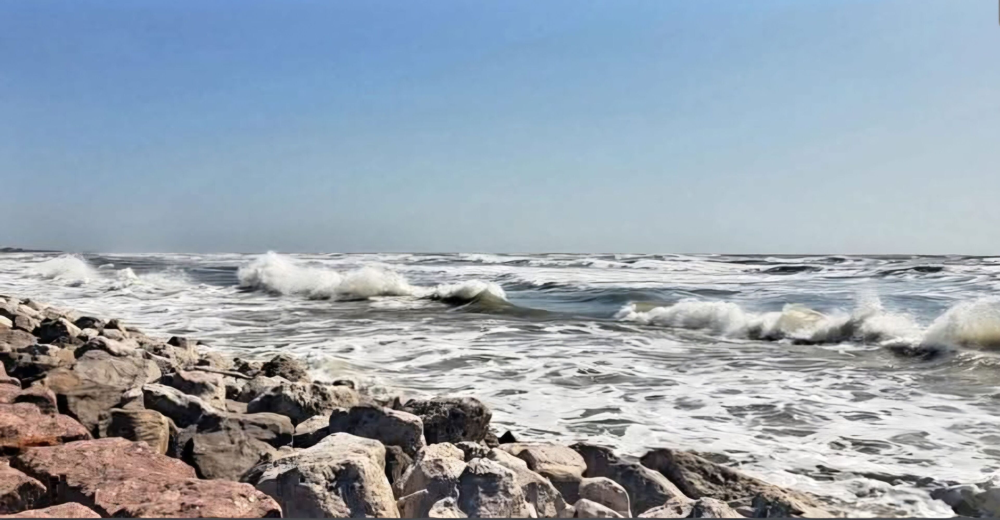 Un rivage rocheux où les vagues s’écrasent contre les rochers.