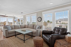 A spacious living room with a large sectional sofa, a coffee table, and a leather armchair.
