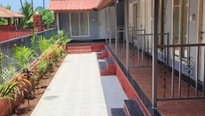 A corridor with a tiled floor, steps leading to a covered area, and a row of plants on one side. - Saavi Resort Shrivardhan (Shrivardhan)