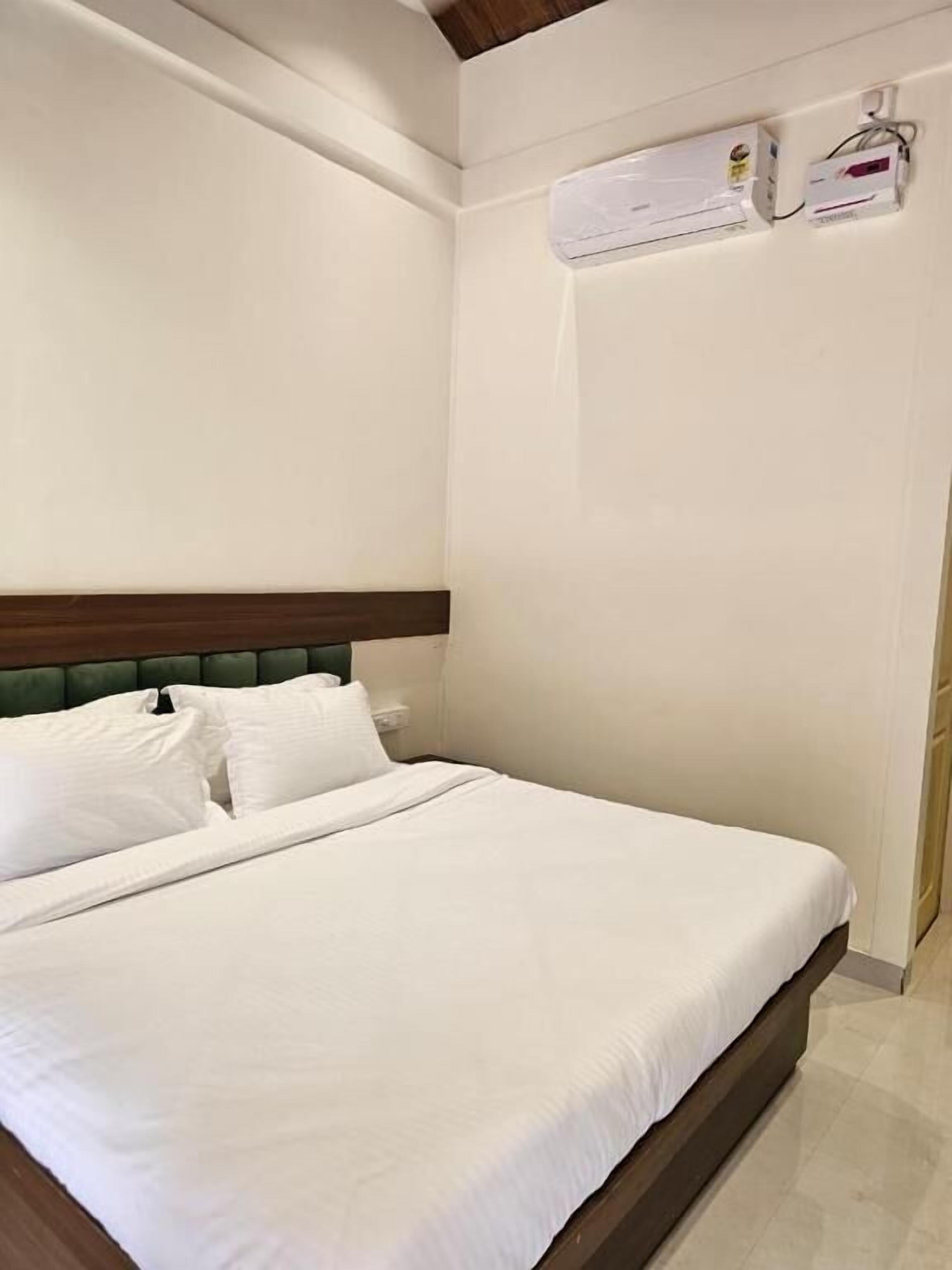 Une chambre d’hôtel avec un lit, une tête de lit et un appareil de climatisation fixé au mur.