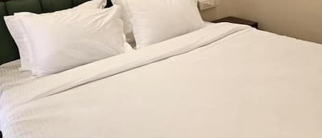 A bed with white bedding and a wooden headboard.