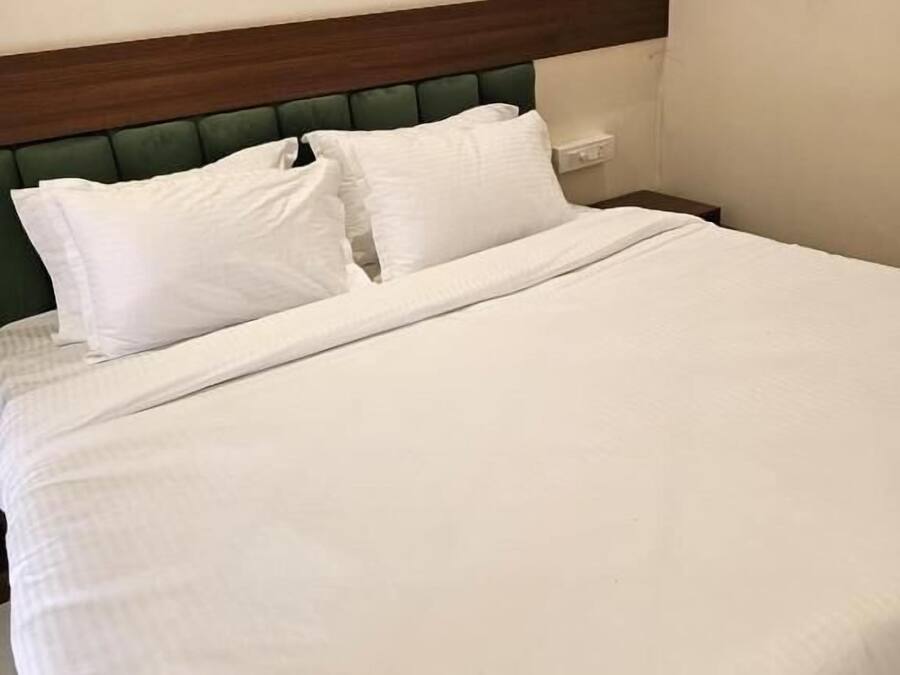 Una cama con ropa blanca y cabecera de madera.