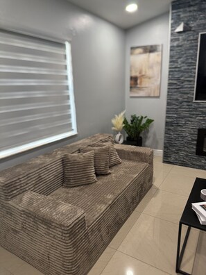 Ein modernes Wohnzimmer mit einer Couch, einem Couchtisch und einem an der Wand befestigten Fernseher.