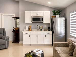 A modern kitchen with white cabinets, a stainless steel refrigerator, and a microwave. - Private Master Suite w/ Kitchenette Near Airport (Tampa)
