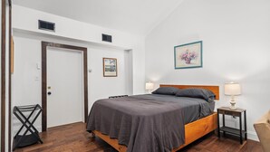 A bedroom with a wooden bed, two bedside lamps, a door, and a wall-mounted picture.